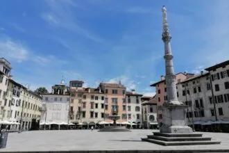 Historic square in Udine with a stone column and colourful Italian buildings