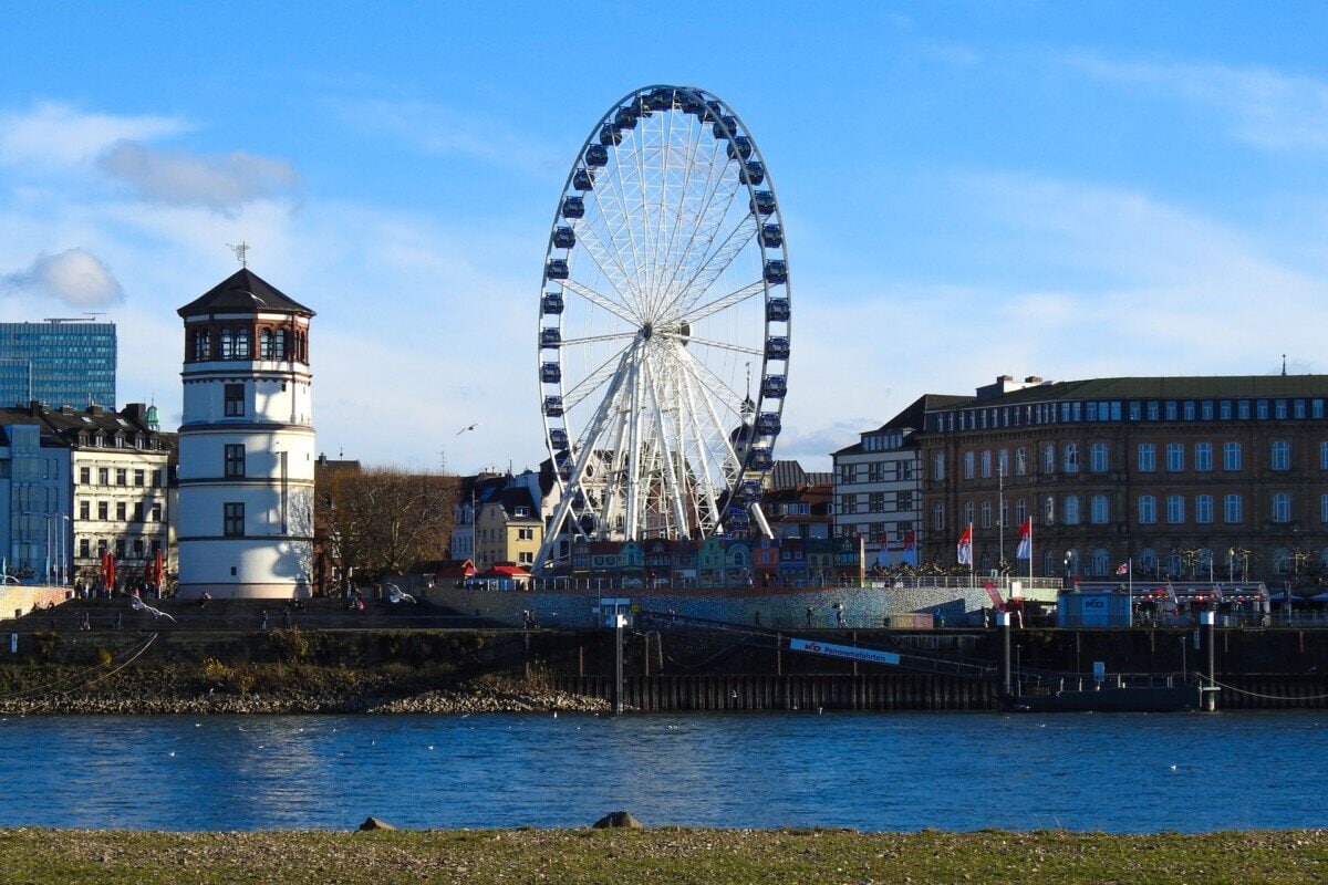 Düsseldorf Rhine waterfront with the Schlossturm and a large Ferris wheel beside the river
