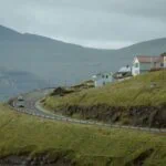 Winding road through green hills and villages in the Faroe Islands