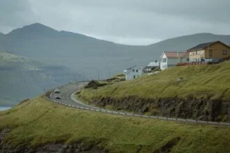 Winding road through green hills and villages in the Faroe Islands