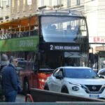 Open-top sightseeing bus travelling through central Milan
