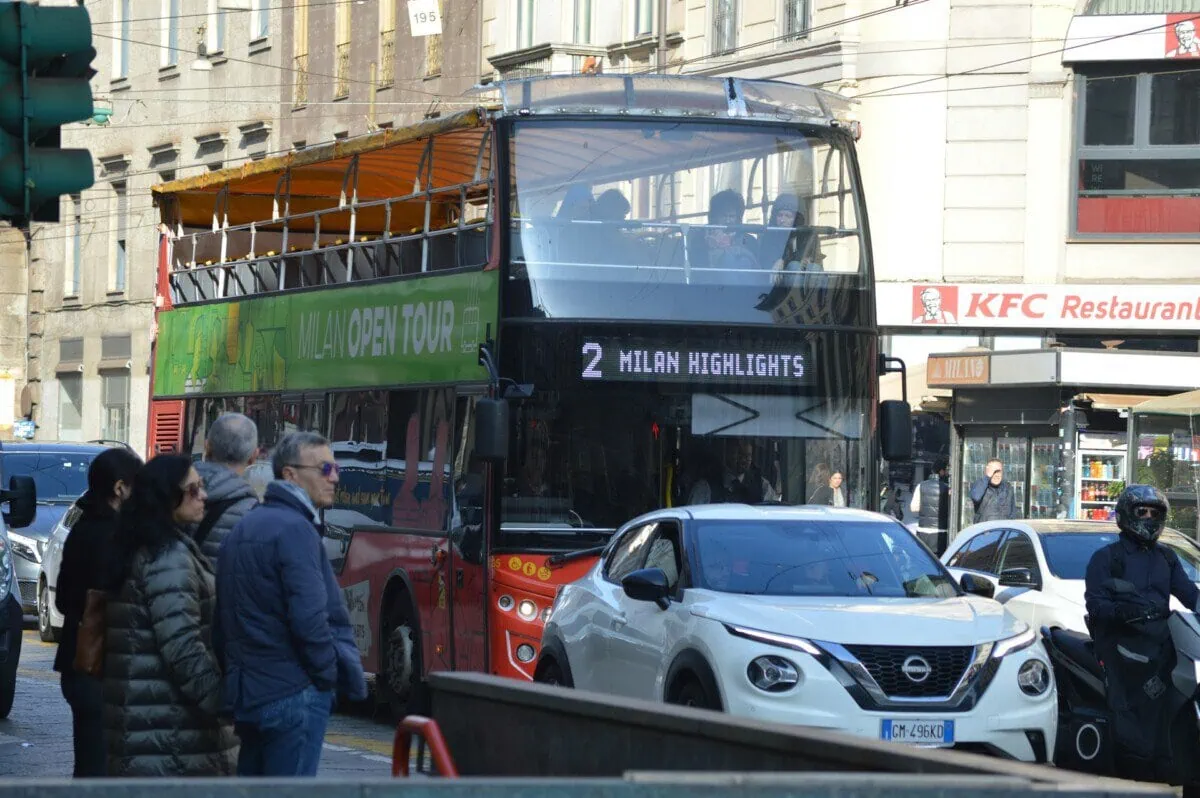 Open-top sightseeing bus travelling through central Milan