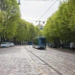 Modern tram travelling along a tree-lined street in Milan