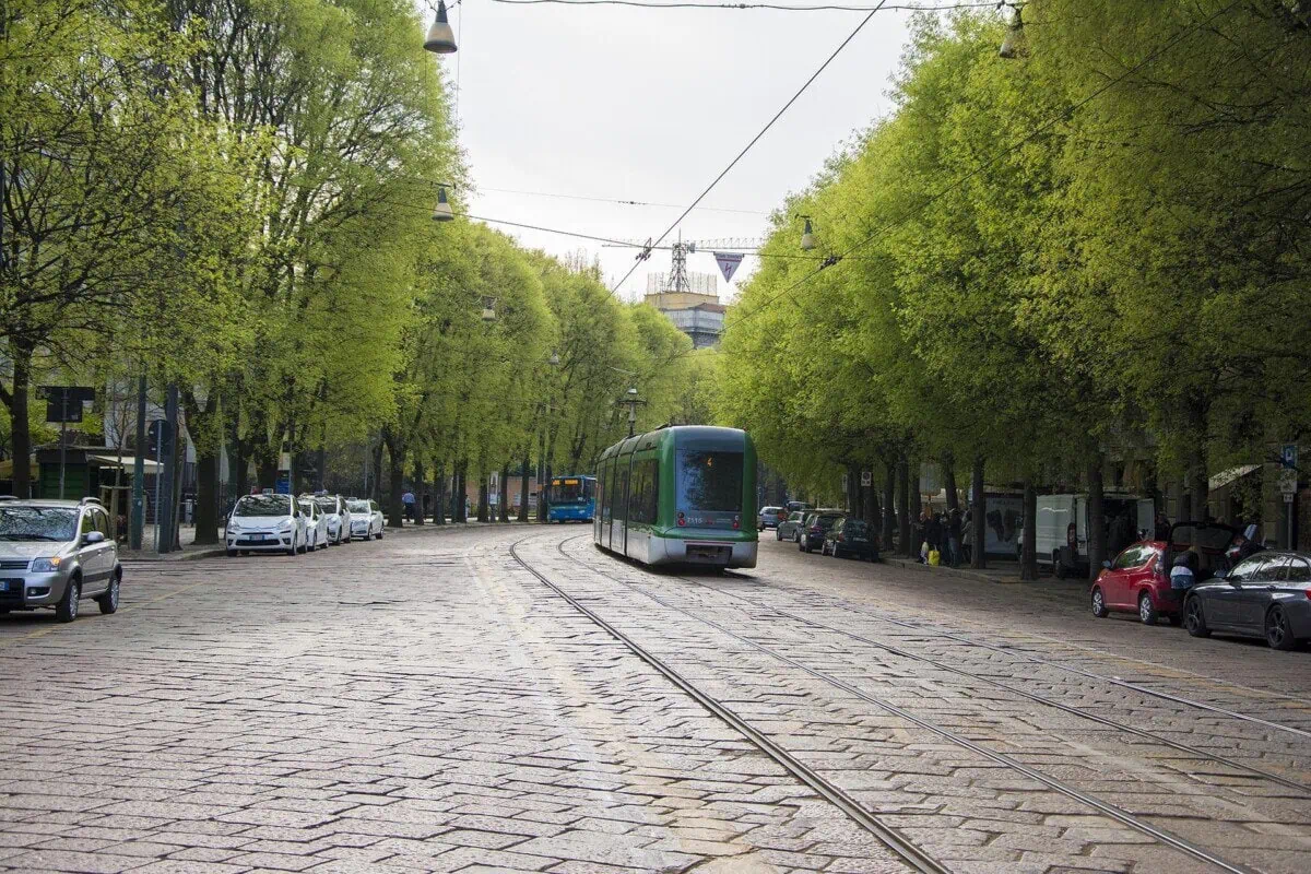 Modern tram travelling along a tree-lined street in Milan