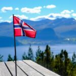 Norwegian flag with a fjord and mountains in the background