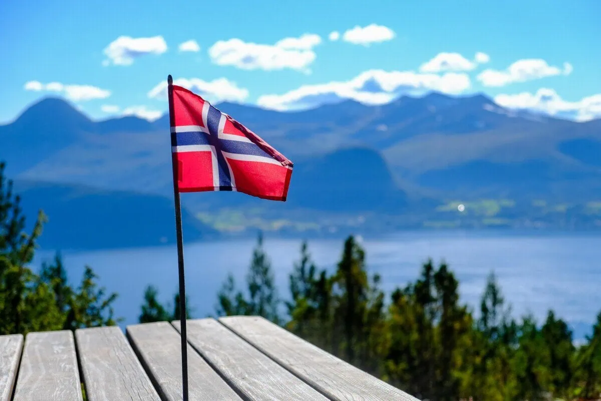 Norwegian flag with a fjord and mountains in the background