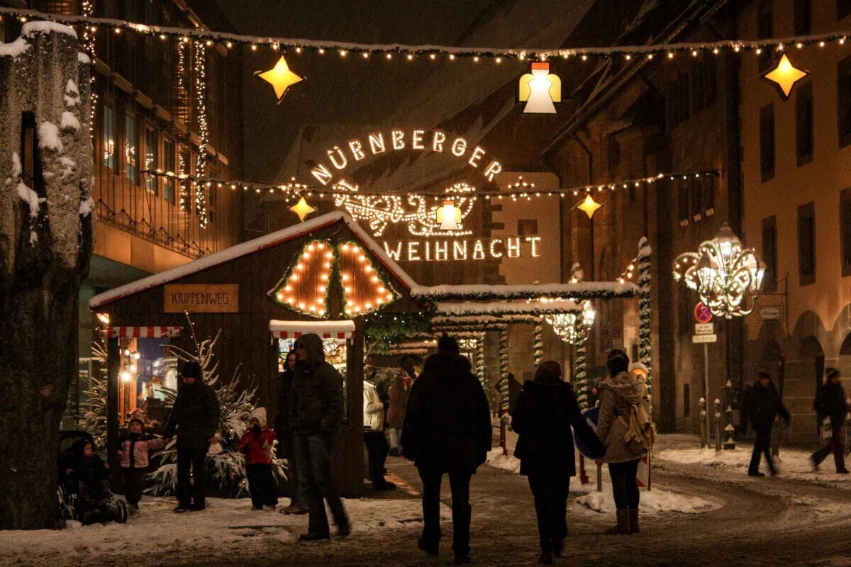 Snowy Nuremberg Christmas market with festive lights and wooden stalls at night