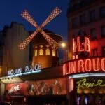 Moulin Rouge cabaret and red windmill illuminated at night in Paris