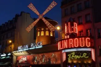 Moulin Rouge cabaret and red windmill illuminated at night in Paris
