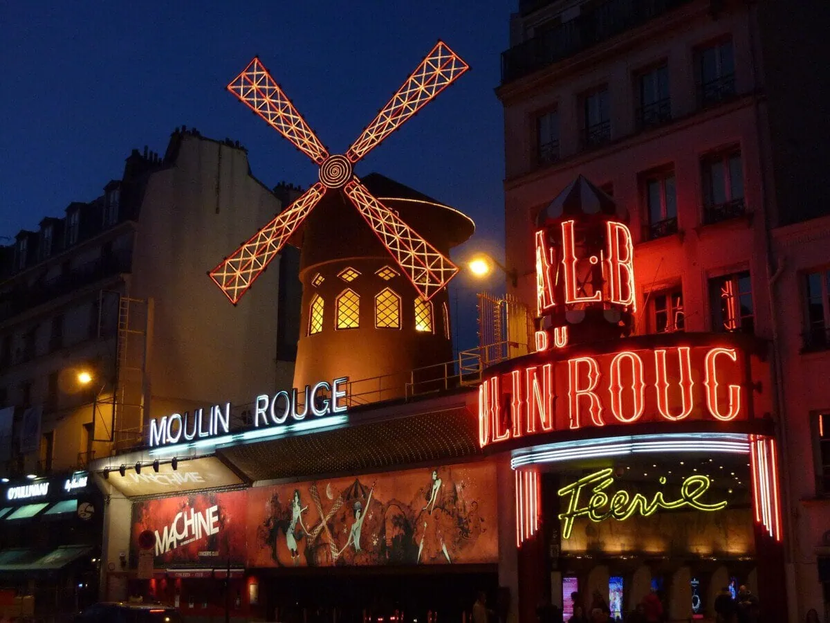 Moulin Rouge cabaret and red windmill illuminated at night in Paris