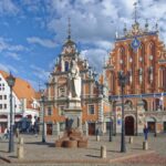 House of the Black Heads and Roland statue in Riga Town Hall Square under a blue sky