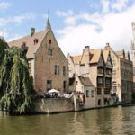 Historic buildings beside a Bruges canal with the Belfry visible in the background