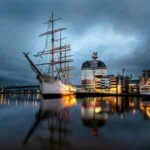 Historic sailing ship moored in Gothenburg harbour with the waterfront skyline reflected in the water