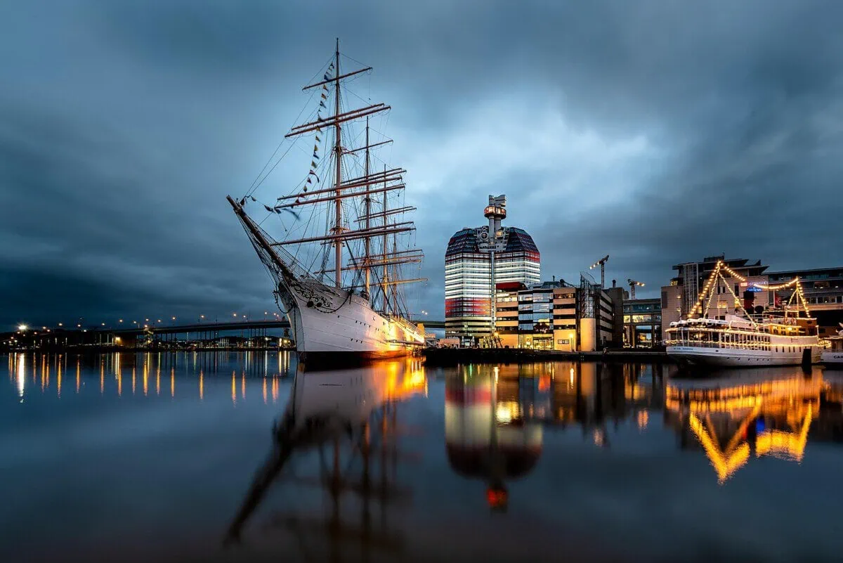 Historic sailing ship moored in Gothenburg harbour with the waterfront skyline reflected in the water