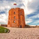 Gediminas Castle Tower in Vilnius with the Lithuanian flag under a dramatic sky