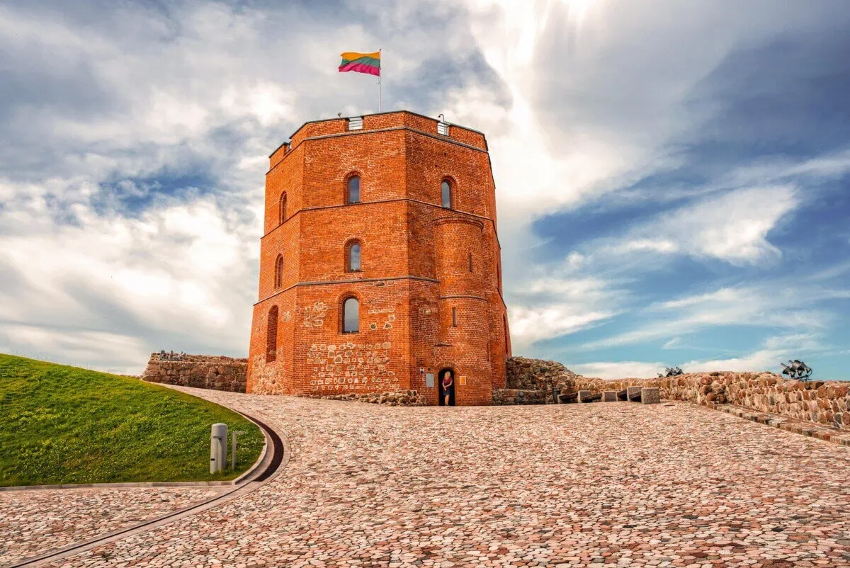 Gediminas Castle Tower in Vilnius with the Lithuanian flag under a dramatic sky