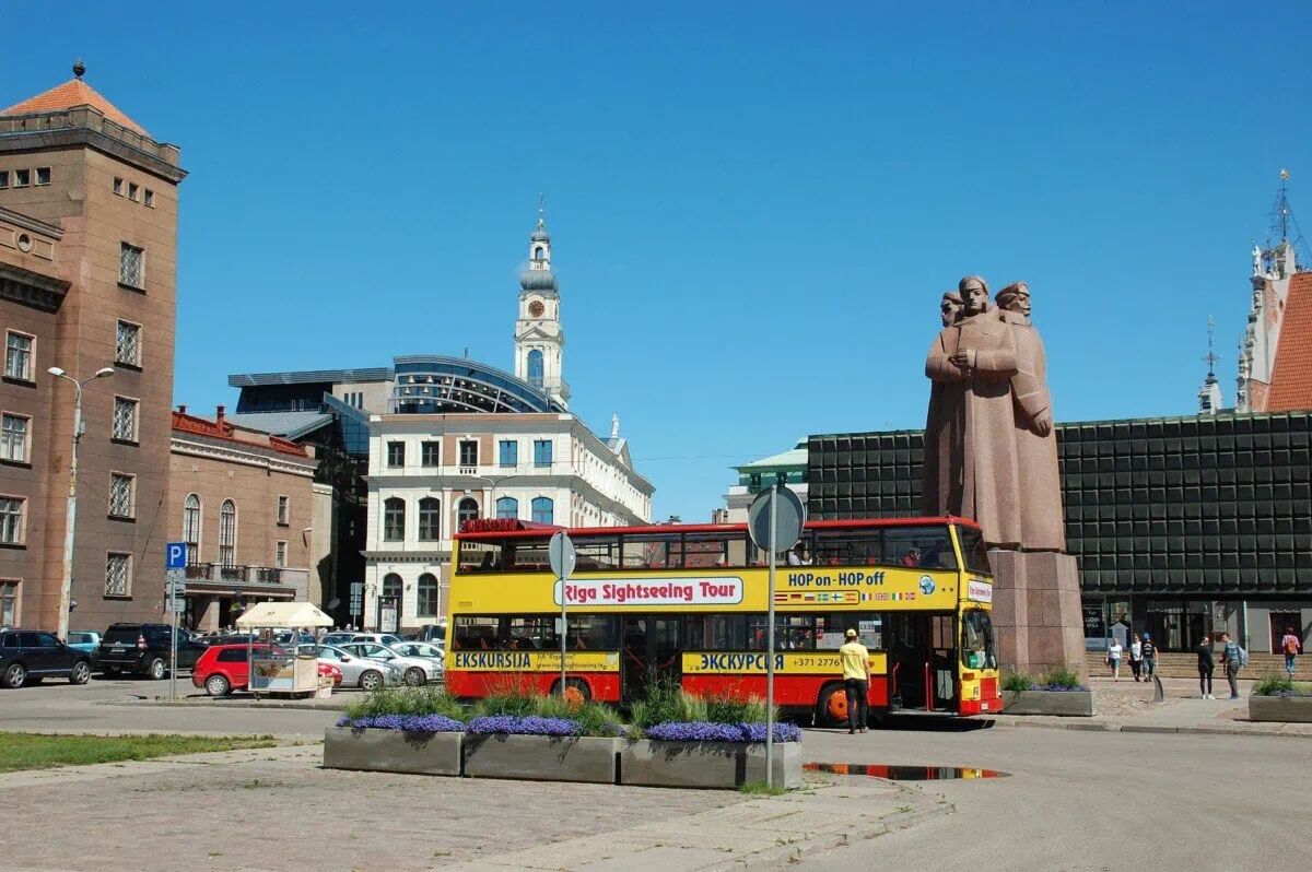 Riga Old Town with a sightseeing bus and the Latvian Riflemen Monument under a clear blue sky