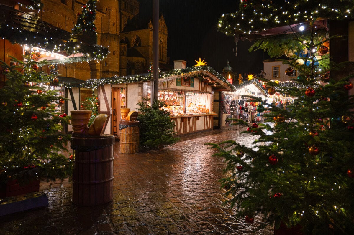 Christmas market stalls decorated with festive lights and Christmas trees in Trier, Germany