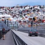 Road crossing a bridge into snowy Tromsø with colourful hillside houses beyond