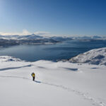 Ski tourer crossing deep snow above an Arctic fjord near Tromsø