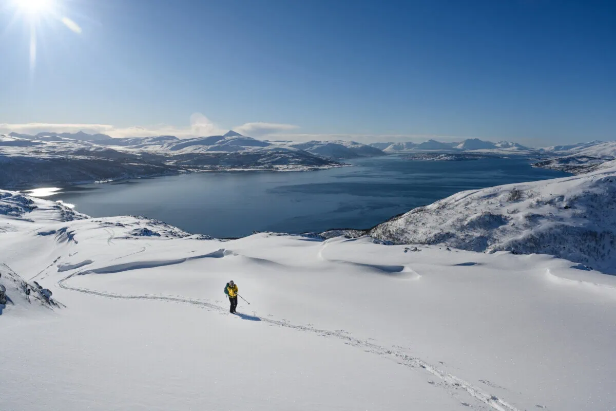 Ski tourer crossing deep snow above an Arctic fjord near Tromsø