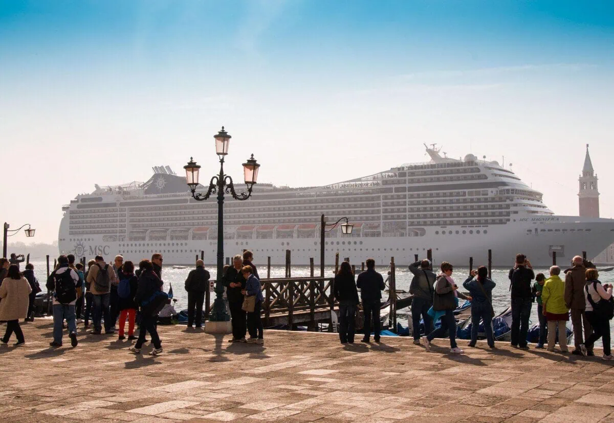 Large cruise ship sailing near Venice with waterfront crowds