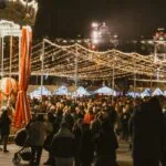 Crowds at Vilnius Christmas market beneath festive lights at night