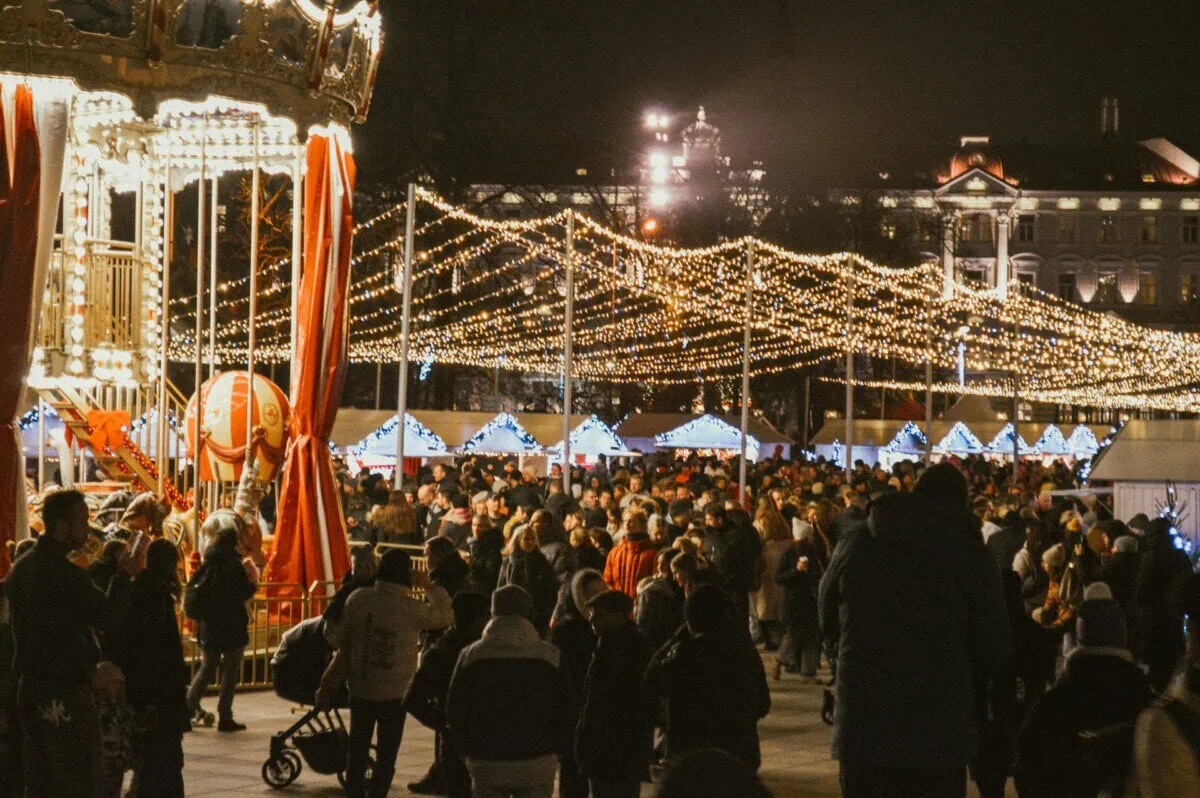 Crowds at Vilnius Christmas market beneath festive lights at night